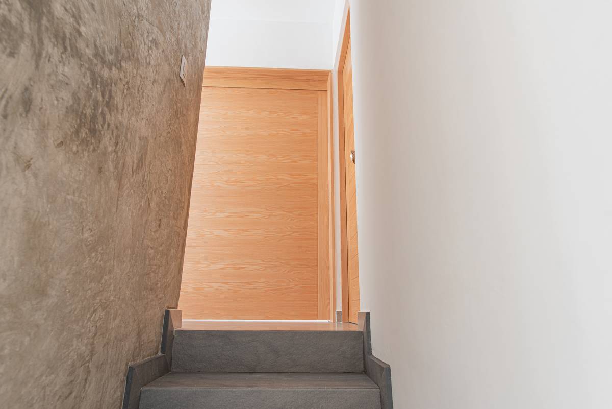 Escalera de Casa Arbolada — muro de piedra y puerta de madera