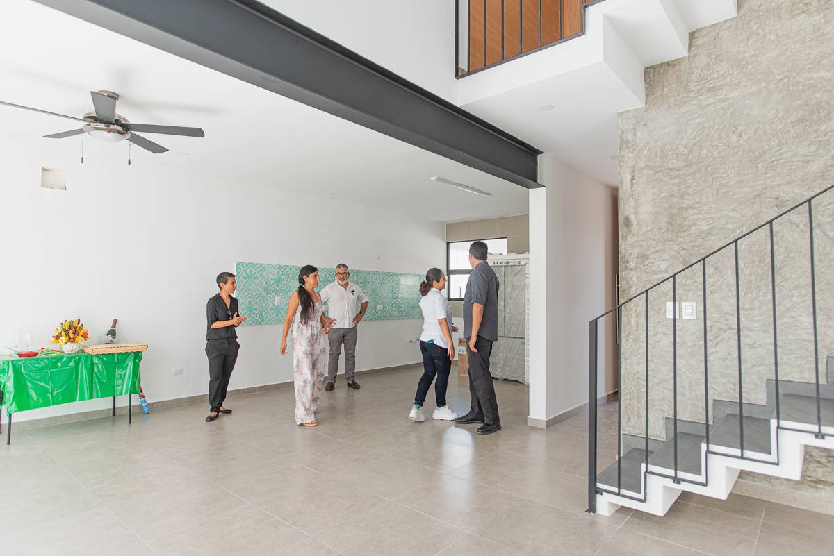 Casa Arbolada — sala de doble altura con muro de piedra y viga de acero en Cancún